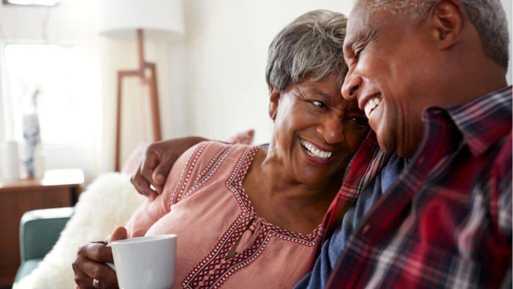 An older couple sitting on the sofa and laughing together