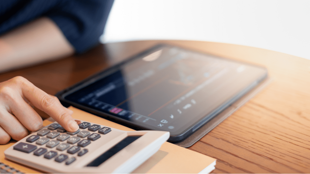 A person using a calculator while looking at a graph on a tablet