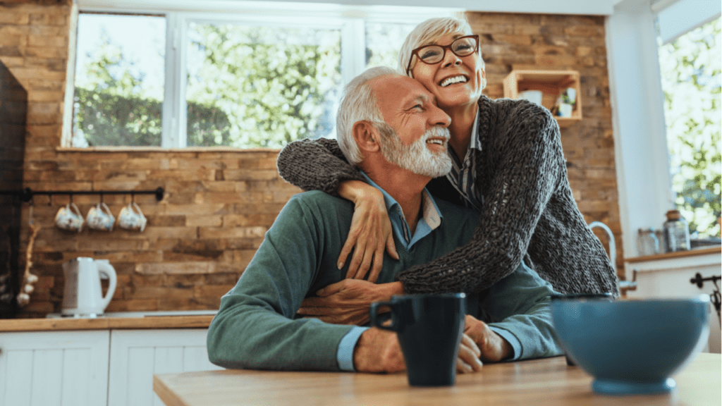 An older couple smiling and hugging at the dinner table
