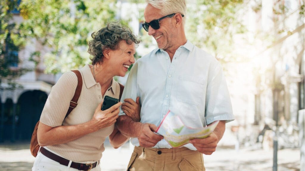 An older couple laughing as they walk around a town with a map