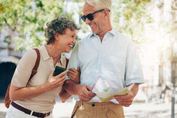 An older couple laughing as they walk around a town with a map