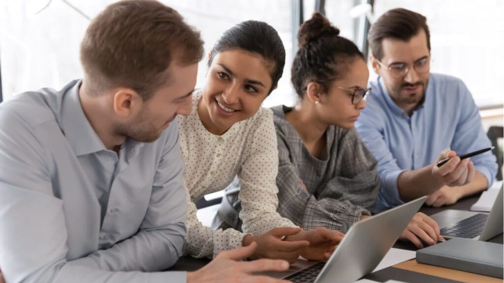 A group of young employees talking and working at a desk