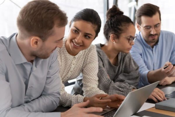 A group of young employees talking and working at a desk